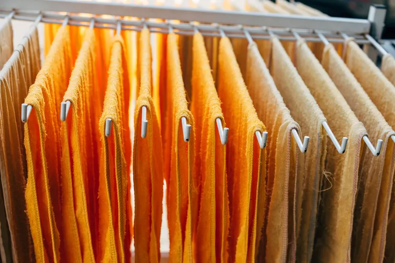 Vibrant orange and beige towels neatly hang on a drying rack indoors