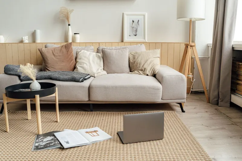 A contemporary living room featuring a sofa, laptop, and modern decor, ideal for remote work