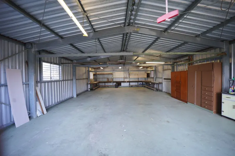 Empty industrial garage with metal walls and concrete floor ready for renovation or use