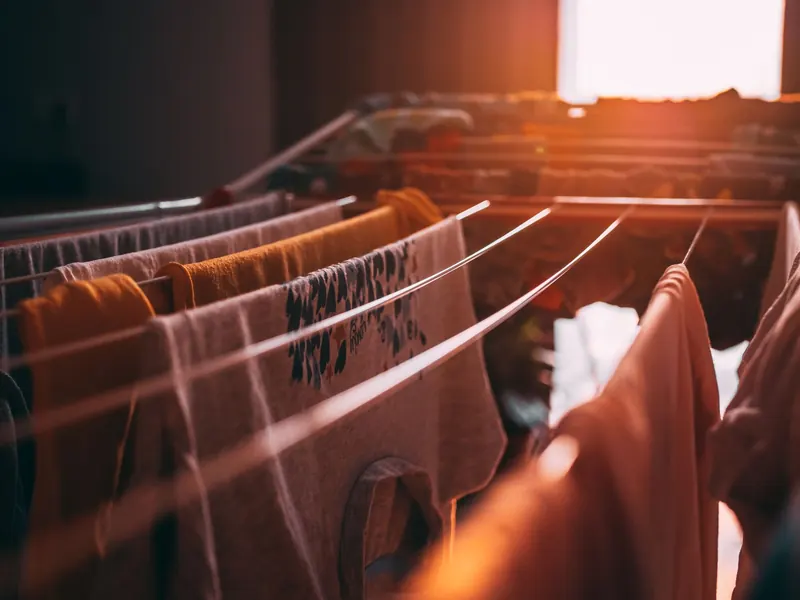 Sunset casts a warm glow on clothes drying indoors on a rack, evoking a cozy ambiance